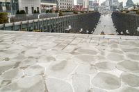 a paved walkway runs through a city with a big building in the background as well as large windows