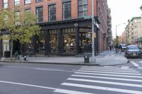 an intersection of a cross walk and store in an urban city area on the corner of the street