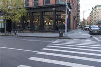 an intersection of a cross walk and store in an urban city area on the corner of the street