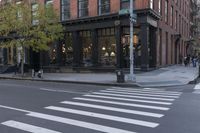 an intersection of a cross walk and store in an urban city area on the corner of the street