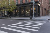 an intersection of a cross walk and store in an urban city area on the corner of the street
