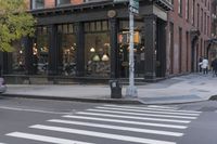 an intersection of a cross walk and store in an urban city area on the corner of the street