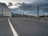 an empty road with white lines on both sides and a person riding a bike on the right