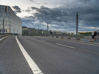 an empty road with white lines on both sides and a person riding a bike on the right