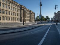 a street light next to an empty road in front of a building with a traffic light on top of it