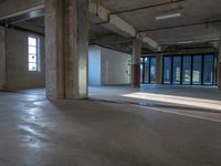 a room with some concrete flooring and large windows with lights coming through it on one side and an open ceiling above the rest of the other