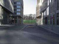 an empty street in a modern city with buildings around it and a green gate at the entrance