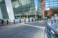 an empty concrete and brick walkway leading to an glassy building, in front of a sidewalk