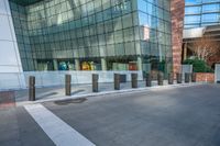 an empty concrete and brick walkway leading to an glassy building, in front of a sidewalk