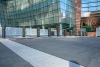 an empty concrete and brick walkway leading to an glassy building, in front of a sidewalk