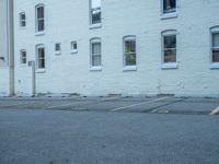 a street with a building near the building in the middle and on the left of which is a parking lot, as shown in this photo