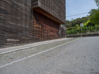 a stone road between two wooden building in the back ground with trees around it and bushes in the background