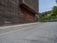 a stone road between two wooden building in the back ground with trees around it and bushes in the background