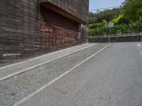 a stone road between two wooden building in the back ground with trees around it and bushes in the background