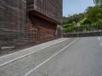 a stone road between two wooden building in the back ground with trees around it and bushes in the background