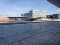 a skateboard sits outside a concrete structure that is next to a street area with a bench