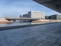 a skateboard sits outside a concrete structure that is next to a street area with a bench