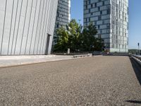 the man rides a skateboard on the road outside a city building next to it