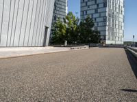 the man rides a skateboard on the road outside a city building next to it