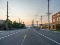 an empty street in front of a large red brick building on the other side of the road is a street light that has a line for motorists