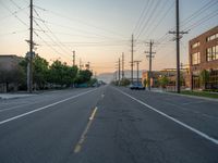 an empty street in front of a large red brick building on the other side of the road is a street light that has a line for motorists