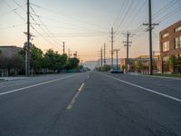 an empty street in front of a large red brick building on the other side of the road is a street light that has a line for motorists