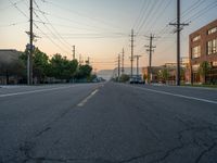 an empty street in front of a large red brick building on the other side of the road is a street light that has a line for motorists