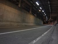 an empty street is shown near a tunnel in the dark at night, with no traffic