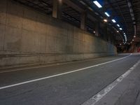 an empty street is shown near a tunnel in the dark at night, with no traffic