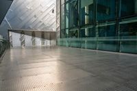 view of large building near walkway and a bench in front of it that is surrounded by metal