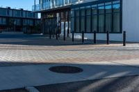 the empty walkway of an urban city plaza has brick and metal poles for the fire hydrant