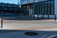 the empty walkway of an urban city plaza has brick and metal poles for the fire hydrant