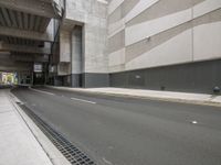 empty road under overpass at city street with buildings in background next to road under bridge