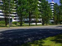 the roadway in front of a building has trees and buildings along it's sides