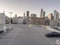 the large parking lot has cars in it that are empty or open to traffic, with a city skyline behind