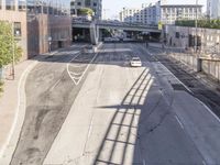 car driving on city street in urban setting next to elevated rail and large buildings with lights