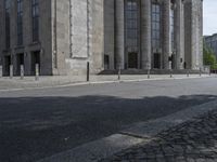 the street has cobblestones on the side and columns on each side of it