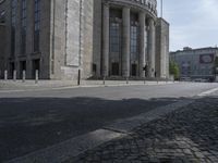 the street has cobblestones on the side and columns on each side of it