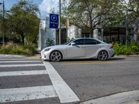 a silver car parked near a white and yellow checkered cross walk way on a city street