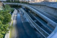 cars are driving under an elevated road in a city street, with a bridge above