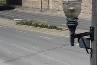 a metal street light on the side of a street next to a road and a brick building