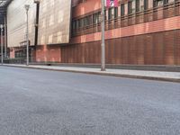 this is an empty city street with red brick buildings and people walking down the sidewalk