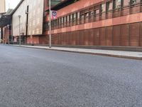 this is an empty city street with red brick buildings and people walking down the sidewalk