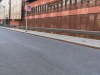 this is an empty city street with red brick buildings and people walking down the sidewalk