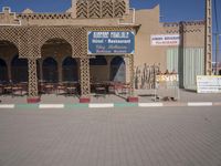 there is a large building with lots of chairs and tables outside it and signs in arabic