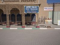 there is a large building with lots of chairs and tables outside it and signs in arabic