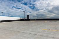 an empty parking lot next to the sky in front of several lights and a street light