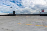 an empty parking lot next to the sky in front of several lights and a street light