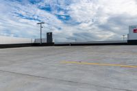 an empty parking lot next to the sky in front of several lights and a street light