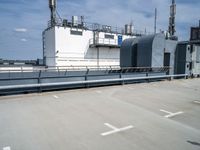 two buildings and one has a railing around it, both in the same spot of an industrial site